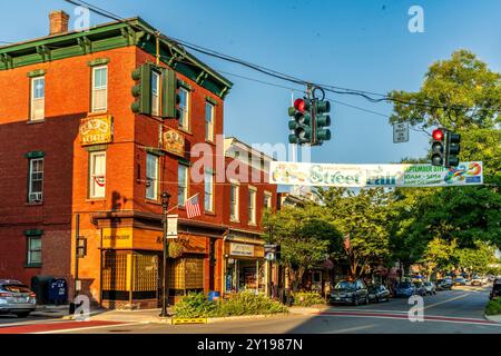 Nyack, NY - USA - 5. September 2024 Main Street in Nyack bei Sonnenuntergang. In einem Gebäude aus rotem Backstein mit grünen Zierleisten befinden sich Geschäfte, darunter ein Sushi-Restaurant. A banne Stockfoto