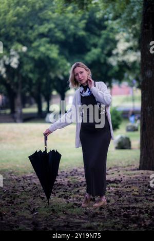 Eine Frau steht mit einem Regenschirm in einem Stadtpark an einem feuchten Tag. Stockfoto