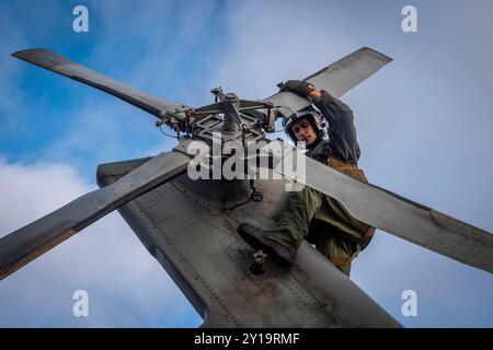 Die 3. Klasse führt vor dem Flug Kontrollen an einem MH-60S Sea Hawk Hubschrauber durch Stockfoto