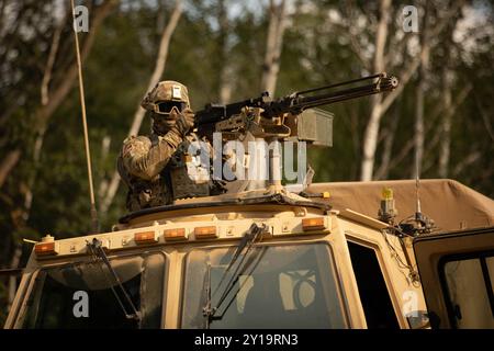 Ein Soldat betreibt ein Maschinengewehr des Kalibers M2 .50, das auf einem Medium Tactical Fahrzeug montiert ist, während eines Konvoi-Trainings Stockfoto