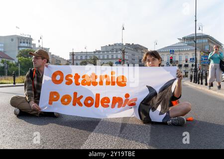 Aktivisten in orangefarbenen Westen halten ein Banner mit der Aufschrift: "Was werden wir den Kindern sagen? Während der Vorführung. Am 2. September 2024, um 8 Uhr morgens, blockierten Aktivisten der letzten Generation (Ostatnie Pokolenie) den Plac Trrish Krzyzy in Warschau und hielten Banner mit der Frage: „Was werden wir unseren Kindern sagen?“ Mit dem Protest soll die katastrophale Zukunft hervorgehoben werden, die erwartet wird, wenn keine Klimaschutzmaßnahmen ergriffen werden, in der große Teile der Erde aufgrund extremer Hitze unbewohnbar werden können. Zu Beginn des neuen Schuljahres blockiert die Gruppe Straßen in der Hauptstadt, um sofortige staatliche Unterstützung für den öffentlichen Nahverkehr zu fordern Stockfoto