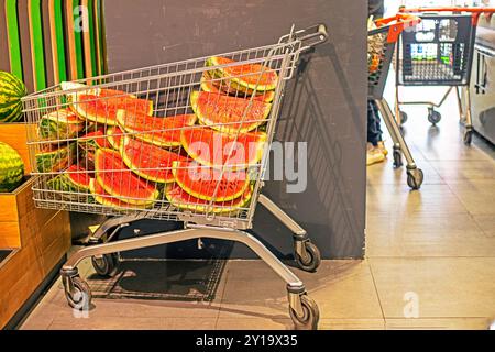 Schneiden Sie Viertel der Wassermelone in Folie in einem Korb für Waren in einem Supermarkt. Tag Der Wassermelone Stockfoto