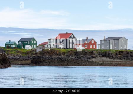 Bunt bemalte Häuser bei Ebbe auf der isländischen Insel Flatey vor blauem Himmel und Wolken. Flatey, Breiðafjörður, Westfjords, Island Stockfoto