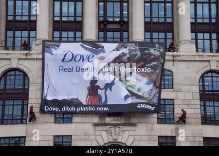 London, Großbritannien. September 2024. Greenpeace-Aktivisten entfalten ein massives Banner auf dem Unilever-Hauptquartier. Aktivisten blockierten auch die Eingänge zum Gebäude und sperrten sich in riesige Nachbildungen von Dove Deodorant Sticks ein, um gegen die Plastikverschmutzung durch Dove Produkte zu protestieren. Quelle: Vuk Valcic/Alamy Live News Stockfoto