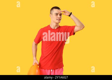 Männlicher Rettungsschwimmer mit Rettungsboje auf gelbem Hintergrund Stockfoto