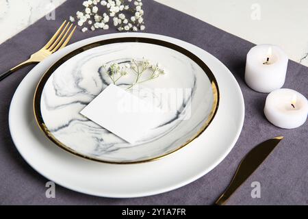 Wunderschöne Tischeinstellung mit leerer Karte, gypsophila-Blumen und brennenden Kerzen auf weißem Hintergrund Stockfoto