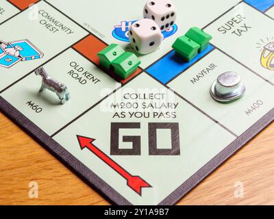 Nahaufnahme von Spielstücken, die an einem Platz vorbeigehen und ein Gehalt für ein britisches Londoner Monopol-Brettspiel erhalten haben Stockfoto