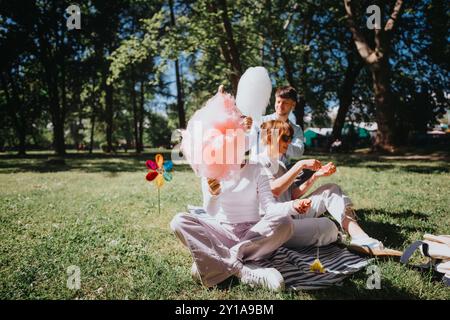 Fröhliche Familie, die Zuckerwatte und Sonnenschein im Park genießt Stockfoto