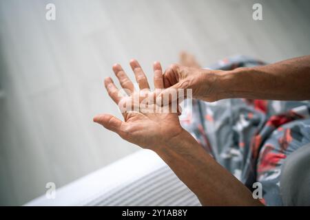 Unsichtbare alte Frau reibt sich, fühlt zarte Hand mit steifem Knoten unter dem Ringfinger. Dupuytren-Kontraktur Stockfoto