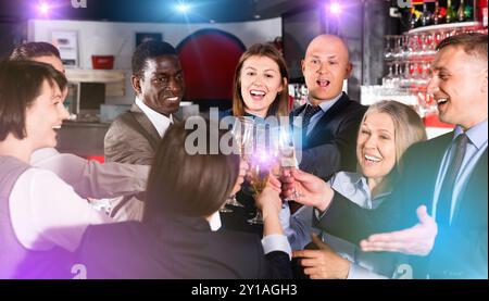 Internationale Gruppe von Geschäftsleuten, die mit Champagner toasten und sich auf der Büroparty im Nachtclub amüsieren Stockfoto
