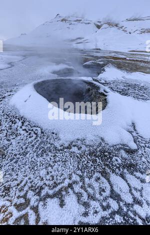 Heiße Quellen und geothermische Gegend vor einer Berglandschaft im Winter, bewölkte Stimmung, Hverir, Namafjall, Myvatn, Island, Europa Stockfoto