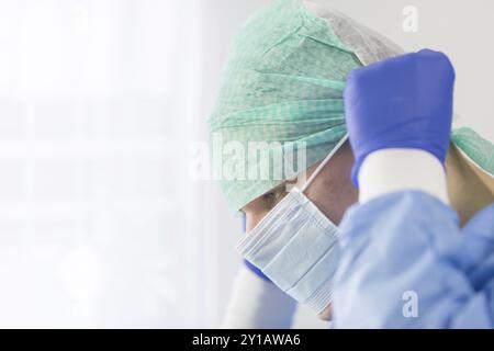 Chirurg Arzt in sterilen Handschuhen Vorbereitung für den Einsatz im Krankenhaus. Er trägt eine chirurgische Gap und blauem Kleid Stockfoto