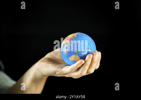 Männliche Hände halten die Erde Globus auf schwarzem Hintergrund Stockfoto