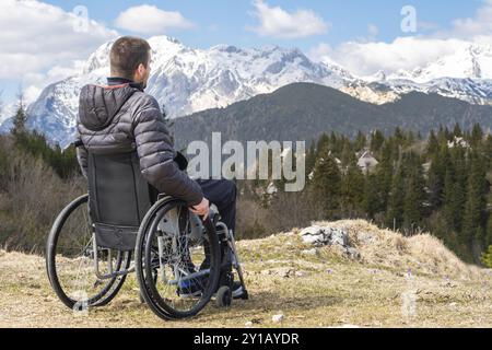 Foto von jungen behinderten Mann im Rollstuhl in der freien Natur beobachten, Berge und Natur Stockfoto