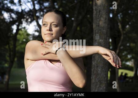 Vorderansicht einer selbstbewussten jungen Frau, die vor dem Training im Park Arme streckt Stockfoto
