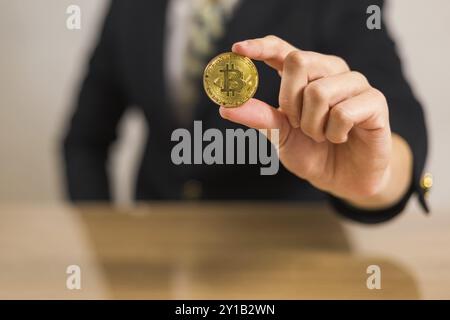 Junger Geschäftsmann, der Bitcoin-Kryptowährung hält Stockfoto