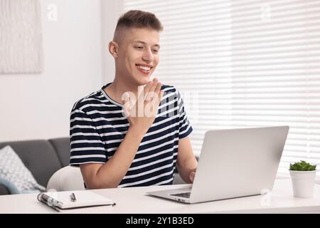 Junger Mann mit Gebärdensprache während Videogesprächen in Innenräumen Stockfoto