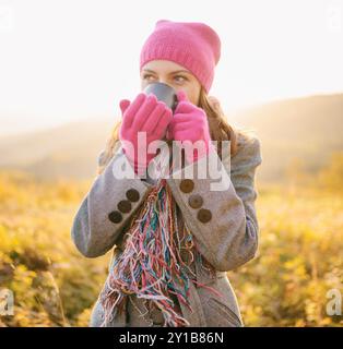 Junge Frau mit Becher in den Händen, die Kaffee und Herbstsaison genießt Stockfoto