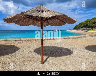 Primosten, Kroatien - Sonnenschirm am Schilf auf der Halbinsel Primosten mit türkisfarbenem Adria-Wasser, Wasserspielplatz an einem sonnigen Sommertag mit Stockfoto