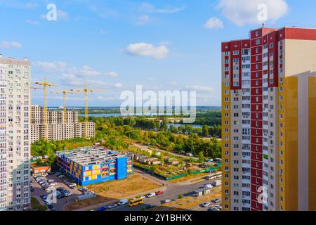 Kiew, Ukraine - 1. Oktober 2023: Blick auf zeitgenössische Wohnhäuser in Kiew mit Baukränen und grüner Landschaft im Hintergrund. Stockfoto