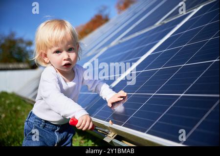 Kleines Kind, das lernt, wie Solarpanel funktioniert. Kleines Kind, das an Reparaturen interessiert ist. Neugieriger Junge, der ein Problem mit einem Schraubendreher löst. Stockfoto