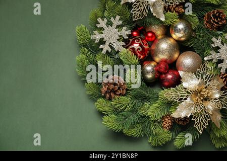 Weihnachtskranz mit Kegeln, Kugeln und dekorativen Schneeflocken auf grünem Hintergrund, Draufsicht. Leerzeichen für Text Stockfoto