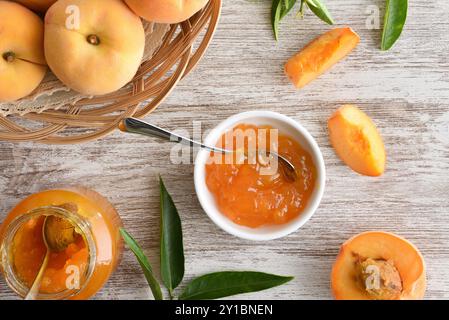 Gläser mit Pfirsichmarmelade auf Holztisch und Korb mit Obst. Draufsicht. Stockfoto