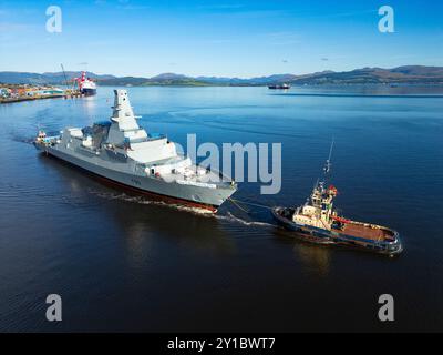 Greenock, Schottland, Großbritannien. September 2024. Aus der Vogelperspektive der HMS Cardiff Typ 26 Fregatte, die am Kreuzfahrtschiff Queen Mary 2 in Greenock vorbeisegelt, auf dem Weg von Glenmallan zur BAE Werft am Fluss Clyde in Scotstoun in Glasgow. Die Fregatte wurde mit einem Lastkahn nach Glenmallan gebracht, um in tiefem Wasser zu starten, und wird nun in der Scotstoun Werft ausgerüstet. Bild: Iain Masterton/Alamy Live News Stockfoto