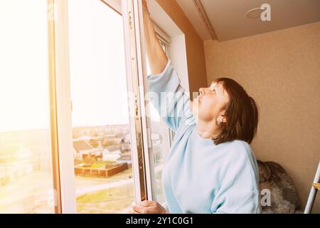 Reinigungsappartement Für Ältere Frauen. Active Seniors-Konzept. Glückliche Schüchterne, Fröhlich Lächelnde Reife Frau, Die Das Fenster Reinigt. Konzept Des Haushalts Und Der Menschen In Stockfoto