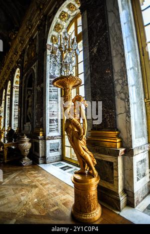 Goldene Statue und Kristallleuchter im Spiegelsaal im Schloss Versailles in Frankreich Stockfoto