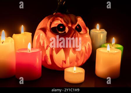 Ein horizontales Foto, das einen ausgehöhlten Halloween-Kürbis zeigt, der von innen von Kerzen beleuchtet wird und mit Herzenslust starrt. Der dunkle Hintergrund fügt eine gruselige Atmosp hinzu Stockfoto