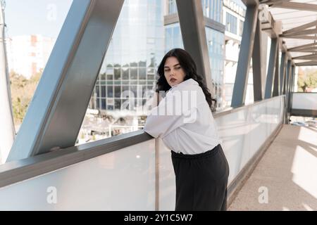 Ruhige Kontemplation: Junge Frau posiert elegant auf dem modernen Urban Overpass. Stockfoto