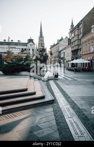 Ein Blick auf den Turm des Namens Marias, die römisch-katholische Kirche im Stadtzentrum von Novi Sad in Serbien, vor dem serbischen Nationaltheater. Stockfoto