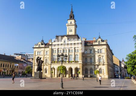 Die Außenfassade des Rathauses von Novi Sad in Serbien auf dem Freiheitsplatz, mit der Statue von Svetozar Miletic an einem sonnigen Tag mit blauem wolkenlosem Himmel. Stockfoto