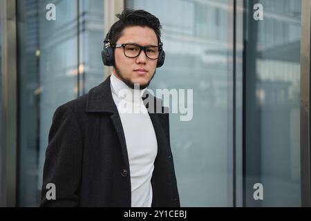 Schicker Mann mit Kopfhörern außerhalb des Büros Stockfoto