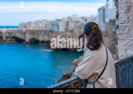 Frau auf einem Balkon mit Blick auf Polignano a Mare in Italien Stockfoto