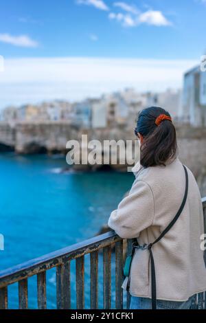 Frau auf einem Balkon mit Blick auf Polignano a Mare in Italien Stockfoto