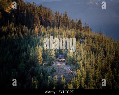 Gelber Überlandwagen, der auf einer Klippe campt, umgeben von Bäumen Stockfoto