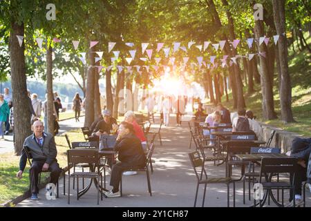 September 2023. Weißrussland. G. Gomil. Der Stadtpark. Eine von der Sommersonne beleuchtete Stadtstraße mit einem Sommercafé und vielen Passanten. Stockfoto