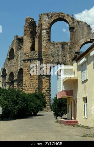 Detaillierte archäologische Ruinen des antiken römischen Aquädukts in Türkiye, Aphrodisias, Steinwasserbrücke, zweistöckige Mauer zwischen grünen Bäumen, Natur und Dörfern Stockfoto