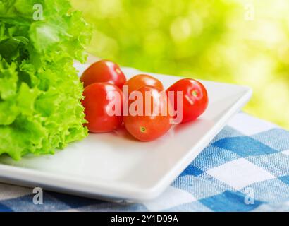 Rote Tomaten und grüner Salat auf der weißen Platte. Stockfoto