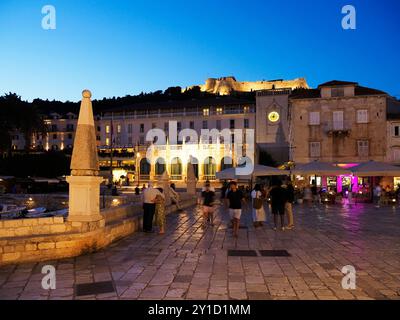 Loggia und Uhrenturm vom Hafen von Hvar mit der Stadtfestung oben in der Abenddämmerung Hvar Stadt Hvar Dalmatien Kroatien Stockfoto