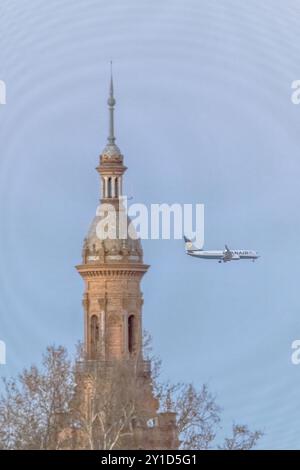 Ein Billigflugzeug fliegt in der Nähe des Südturms der Plaza de España in Sevilla, Spanien. Das Bild erfasst Reise- und Architekturelemente in Harmo Stockfoto