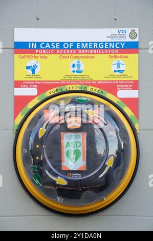 Automatisierter externer Defibrillator (AED). Lebensrettende medizinische Notfallausrüstung in einem transparenten Wandbehälter. Poundbury, Dorset, England Großbritannien Stockfoto