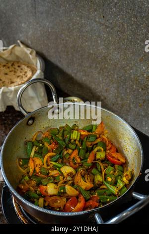 Heiße, dampfende Okra gemischt mit Gemüse, Kräutern und Gewürzen, die in einer indischen Küche gekocht werden. Perfekt für indische Küche und Footage. Stockfoto