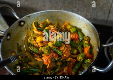 Heiße, dampfende Okra gemischt mit Gemüse, Kräutern und Gewürzen, die in einer indischen Küche gekocht werden. Perfekt für indische Küche und Footage. Stockfoto