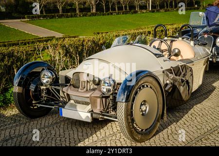 Lissabon, Portugal - 20. Januar 2024: Luxuriöser Morgan Super 3 3-Radsportwagen ohne Softtop auf einem Kopfsteinpflasterweg in der Nähe eines grünen Parks. Stockfoto