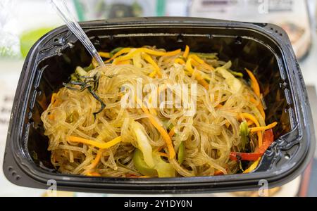 Koreanische Nudeln Japchae mit Gemüse. In einer schwarzen Kunststoffschale Stockfoto