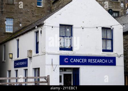 Lerwick, Schottland - 12. Juli 2024: Cancer Research UK Second Shop im Stadtzentrum unterstützt Krebsforschung durch Verkauf von Gebrauchtartikeln. Stockfoto