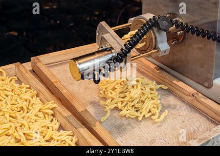 Blick durch ein Fenster in ein Geschäft, das frische Strozzapreti-Pasta herstellt. Strozzapreti wird manchmal als Priest Strangler Pasta oder Priest Choker Pasta bezeichnet. Stockfoto